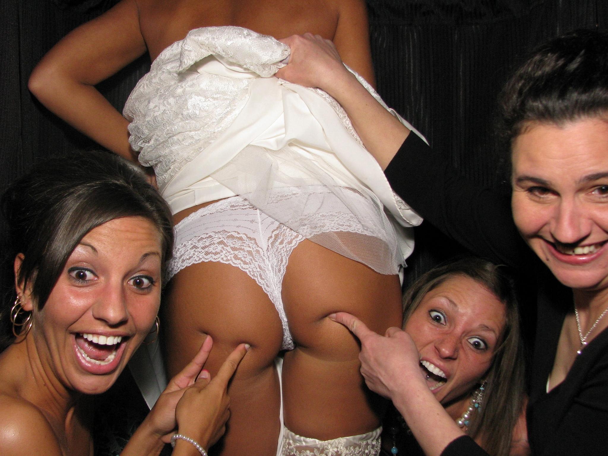 Bride flashing her thong in a photobooth with her bridesmaids. 