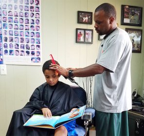 Kids get a $2 discount if they read a book aloud to this barber in Michigan while he sorts them out